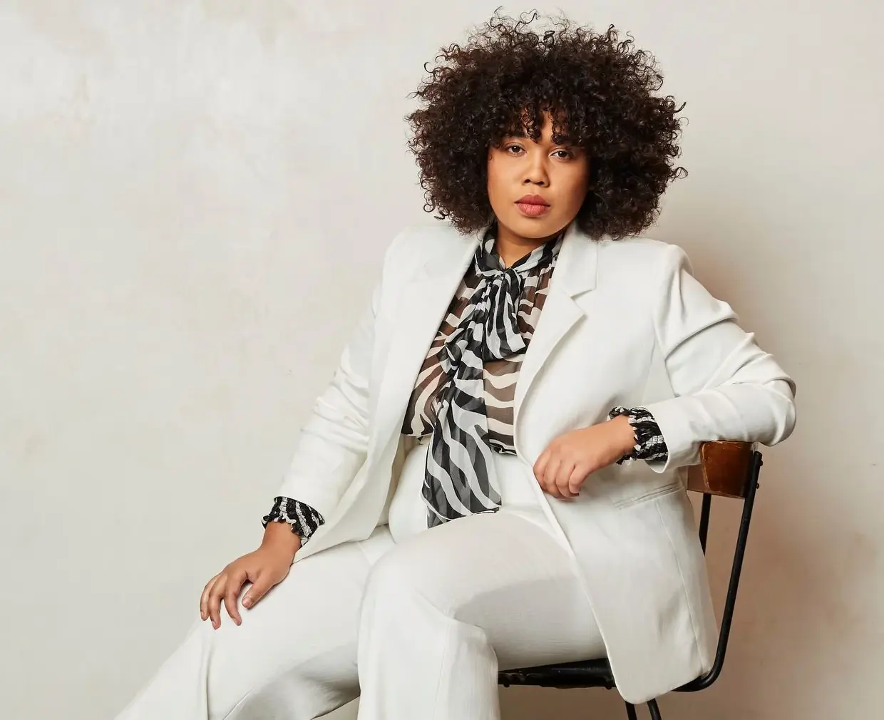 Confident plus size woman wearing a white blazer and black and white top