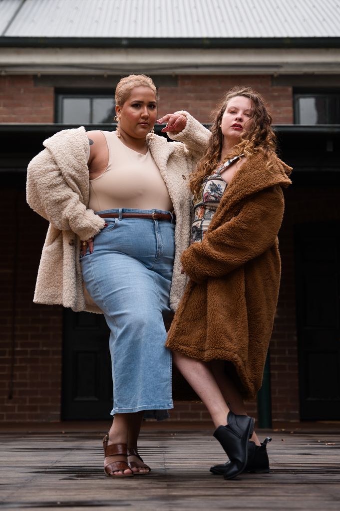 Two women posing confidently in stylish coats against an urban backdrop in Sydney.